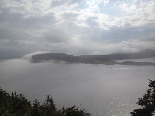 Fog rolling over the hills near Trinity, NL.  There's a lighthouse on that spit of land that's cutting into the harbour.